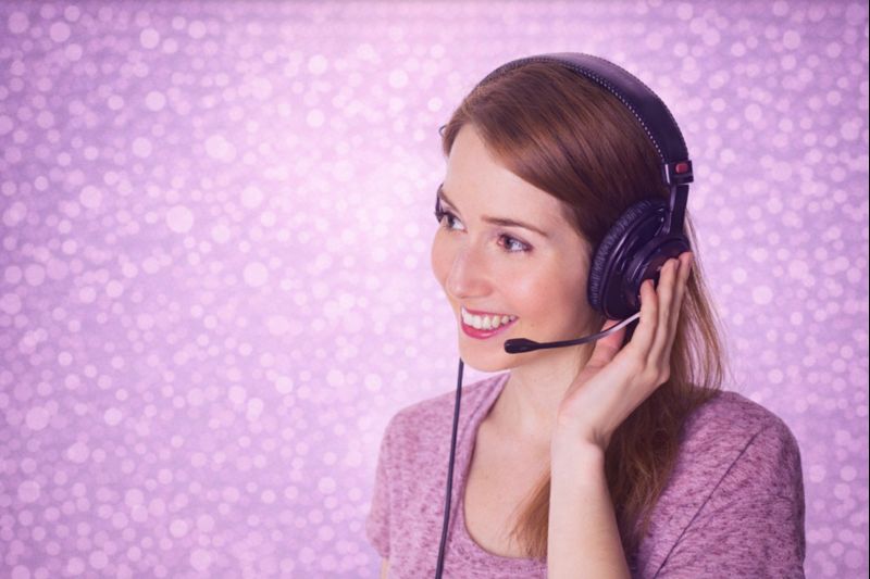 Portrait d'une jeune femme souriante portant un casque audio avec micro, illustrant les bonnes pratiques de la transcription audio dans un environnement professionnel moderne.